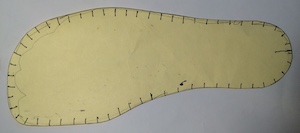 A piece of card in the shape of the outline of a foot, with dozens of black marks at regular intervals around the perimeter