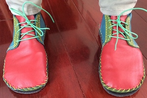 A pair of red and blue boots with green laces, seen from the front