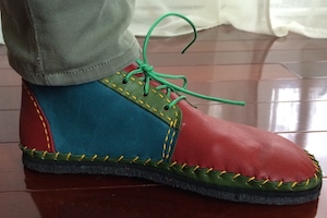 A multicolored chukka boot with yellow whip stitches attaching frill sole to upper.