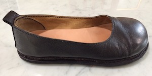 A black leather, flat-soled shoe with a rounded toe.