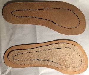 Two partially assembled soles, switched with black thread