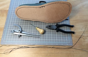 The underside of a shoe with the veg-tan outsole attached using black thread.