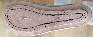 The bottom of a shoe last with a veg-tan leather sole nailed to it with two nails, one in the middle of the forefoot and the other just the heel side of the instep