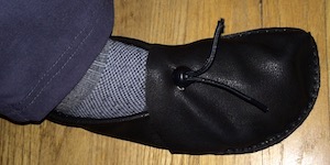 A right foot wearing a dark brown foot-shaped shoe.