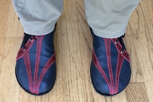 A pair of blue leather shoes with red leather highlights converging at the toes