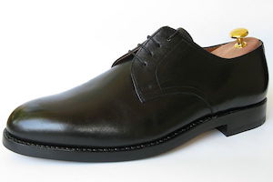 Side-on view of a black, leather men's dress shoe, showing the heavy sole and raised heel.