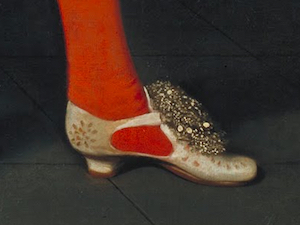 Part of an oil painting showing a lower leg and foot clad in a red sock and ornate cream shoe with a raised heel and decorative upper.